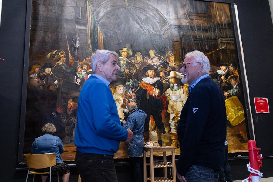 Twee mannen in gesprek voor het grote, bijna voltooide schilderij